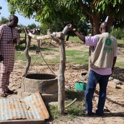 Resident and Oxfam staff in front of a water well