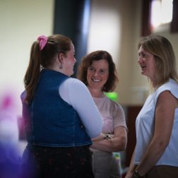 Three females standing in front of each other having a conversation
