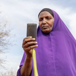Ebla Hussein Ahmed reading a message from her mobile phone at her home in Elben, Wajir County, Kenya. She receives her monthly cash payment notification via her phone.