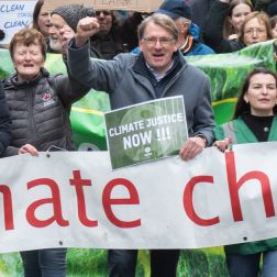 A group of people hold up their hands and hold a banner saying climate chaos
