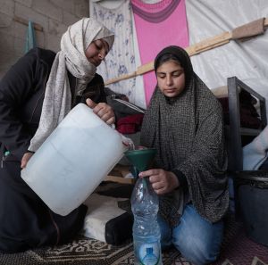 Two women filling up water bottles