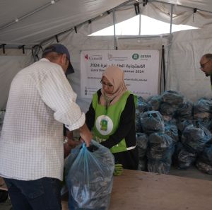 A man is receiving a vegetable basket distributed by Oxfam and partners in Deir Al Balah in the middle of Gaza.