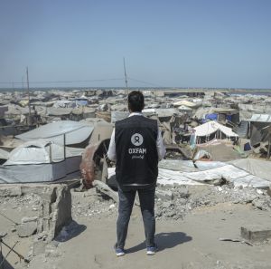 Osama, Oxfam Staff, walks among tents and rubble in Gaza City