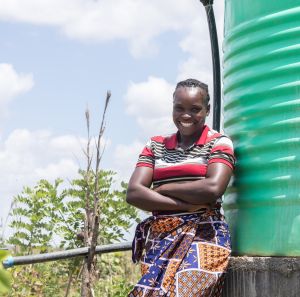 Angela Chiyala, 38, Vice Chairperson of a Farmer Field School in Namwala, Southern Province, Zambia stands near the solar-powered water tank that supplies water to the farmer field school garden.