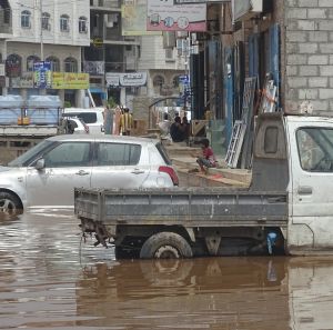 Two cars stopped in a street filled with water.
