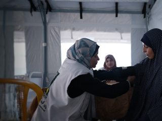 A doctor consults with patients at a community health clinic in Gaza, providing care and guidance.